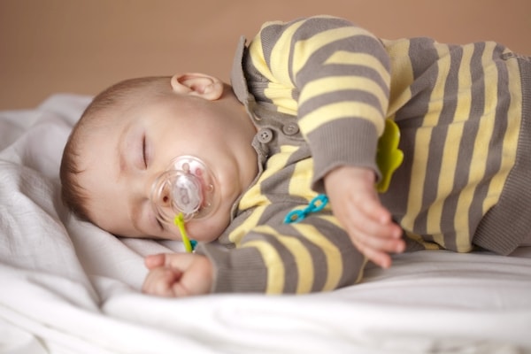 Infant has fallen asleep with a pacifier in his crib for a nap.
